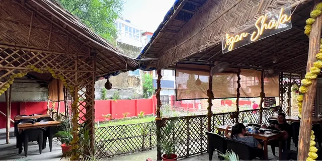 Bamboo seating and the Vegan Shala sign beside a small lawn