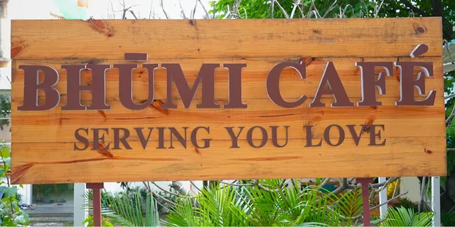 Wooden Bhumi Cafe sign surrounded by green plants